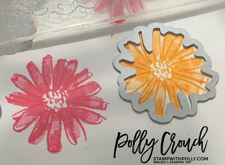 This is an image of stamped daisies in Mango Melody and Polished Pink with a die laying on one of the daisies getting ready to be cut.